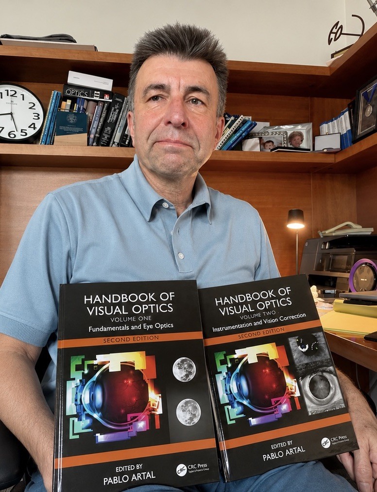 Pablo Artal with the two volumes of the Handbook of Visual Optics, which he edited.